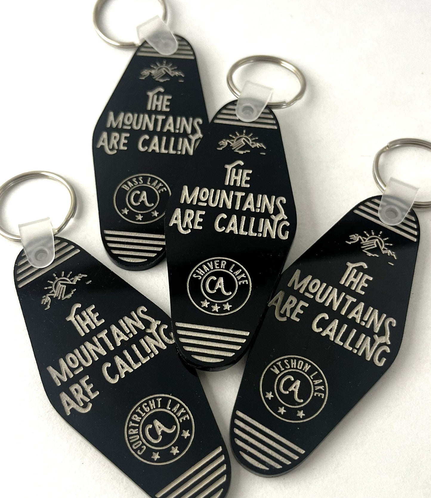Black keychains with 'The Mountains Are Calling' text and logo on a white background